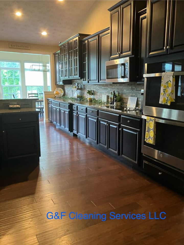 A kitchen with dark cabinets and hardwood floors, cleaned and tidied